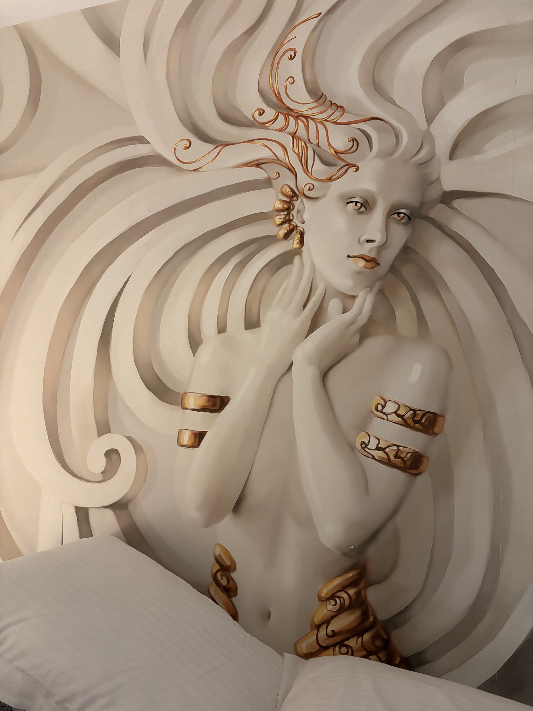 A cream and bronze goddess mural above the bed where Constructed Interiors was written in Naxos, Greece.