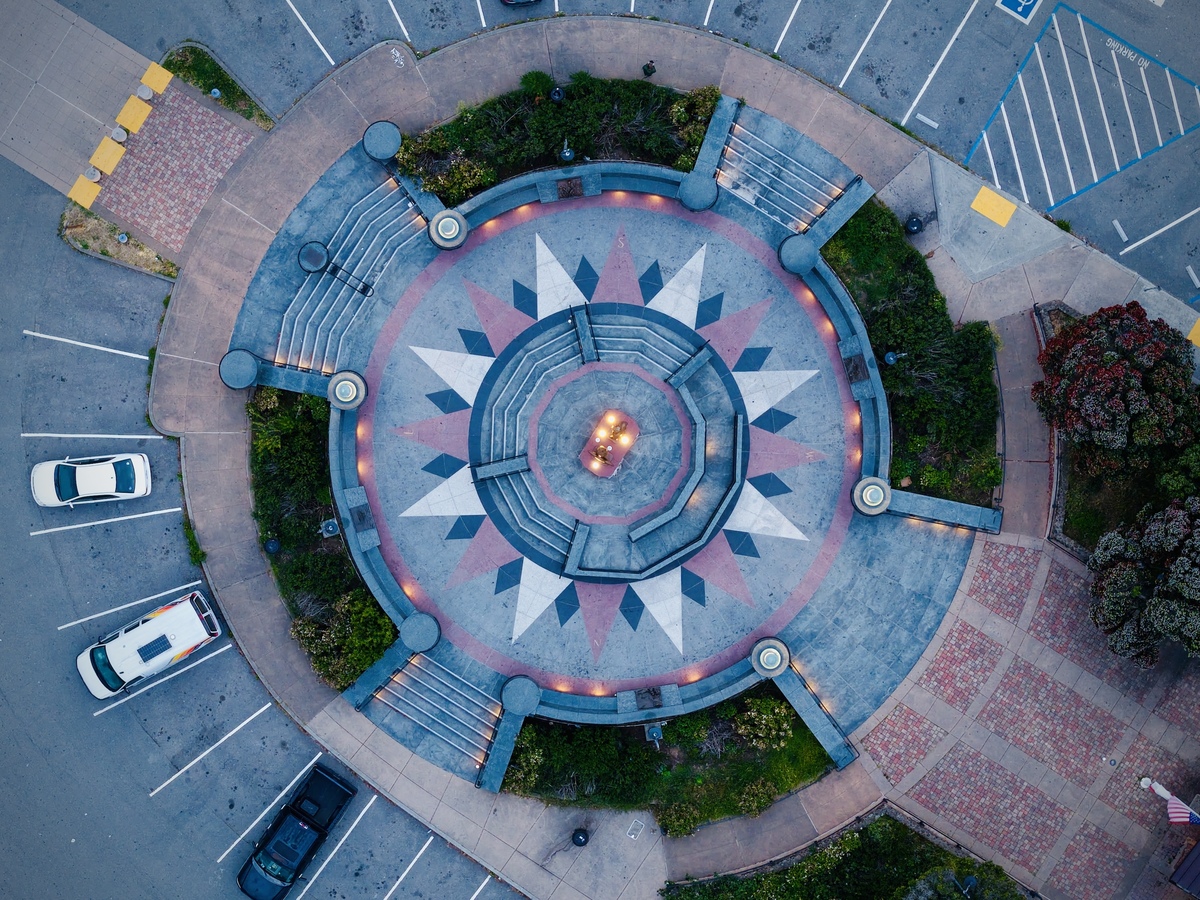 Aerial drone photograph of a circular plaza with a compass-like pattern at dusk.